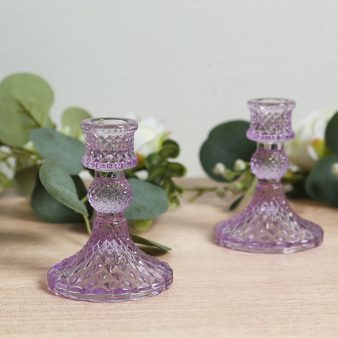 Purple crystal candle holders with intricate designs on wooden surface.