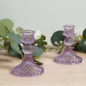 Purple crystal candle holders with intricate designs on wooden surface.