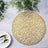 Gold woven placemat on a textured surface with greenery and cutlery.