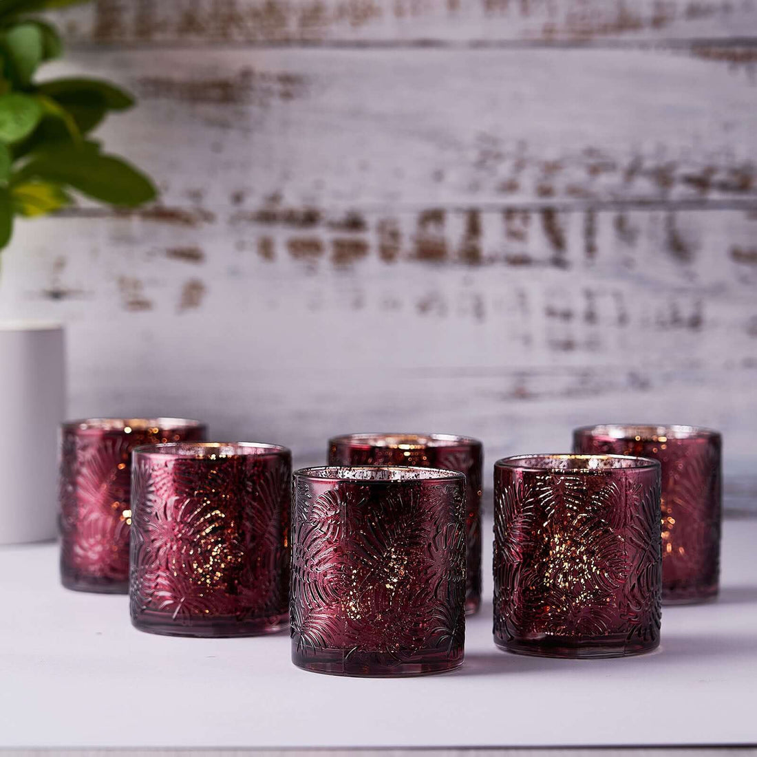 Set of six decorative burgundy candles with intricate designs.