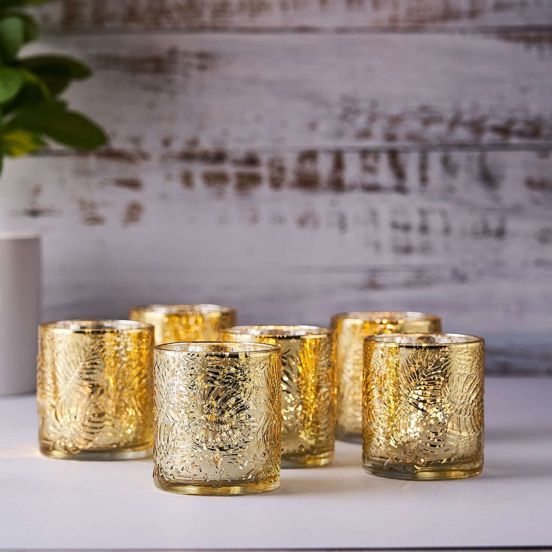 Set of six gold decorative candle holders on a wooden background.