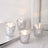 Set of four elegant glass candle holders with intricate patterns.