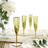Gold fluted champagne glasses on a dining table with flowers