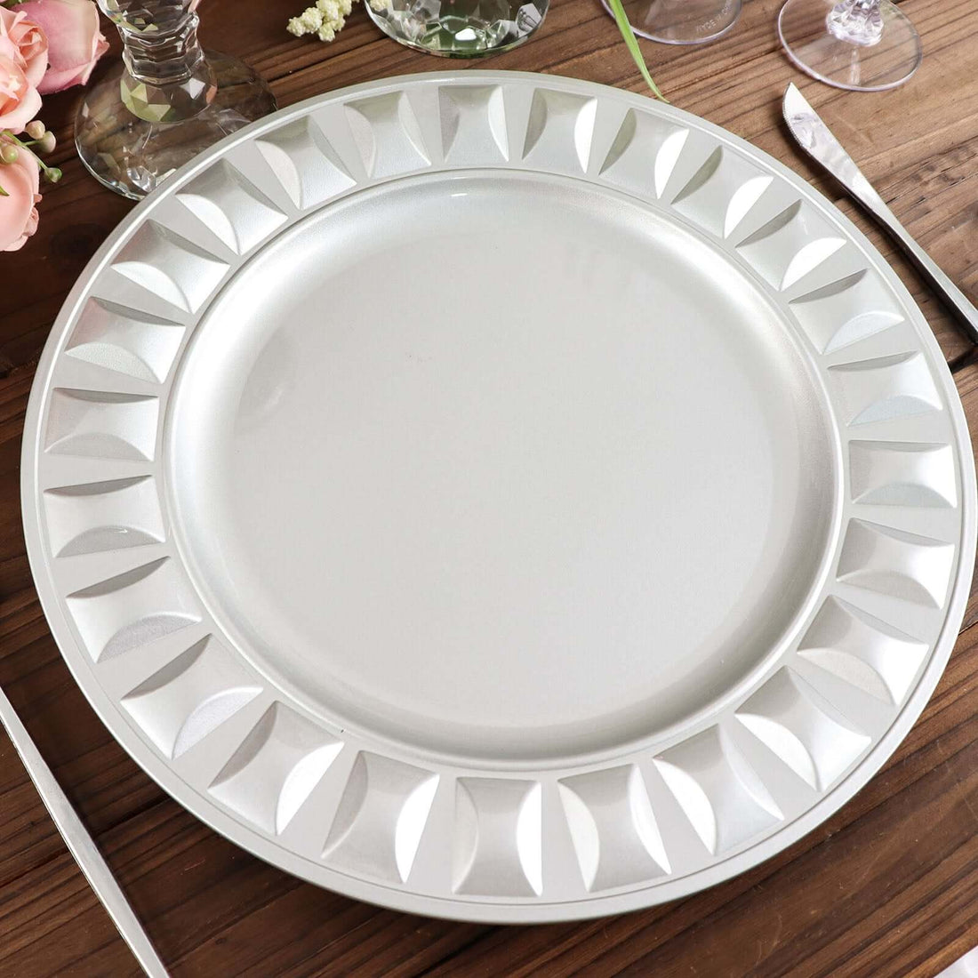 Elegant silver charger plate with embossed design, perfect for dining decor.