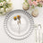 Elegant silver charger plate with dried flowers, set on a table with candles and flowers.