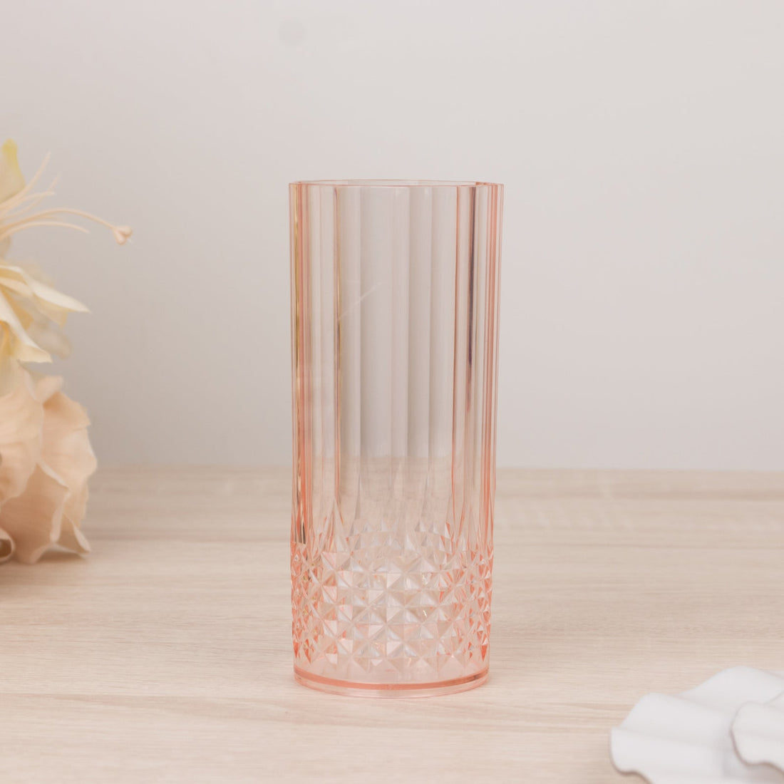 Pink ribbed glass vase with geometric base on a wooden surface.