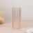 Pink ribbed glass vase with geometric base on a wooden surface.