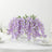 Purple wisteria floral arrangement in a glass vase for table decor