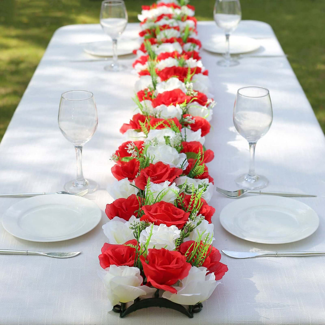 Red and white floral table runner with plates and glasses on a dining table.