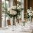 Elegant white rose bouquet in a tall glass vase on a dining table.