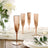 Rose gold champagne flutes set on a table with floral arrangement