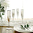 Elegant silver champagne flutes on a table with white flowers and dining setting.