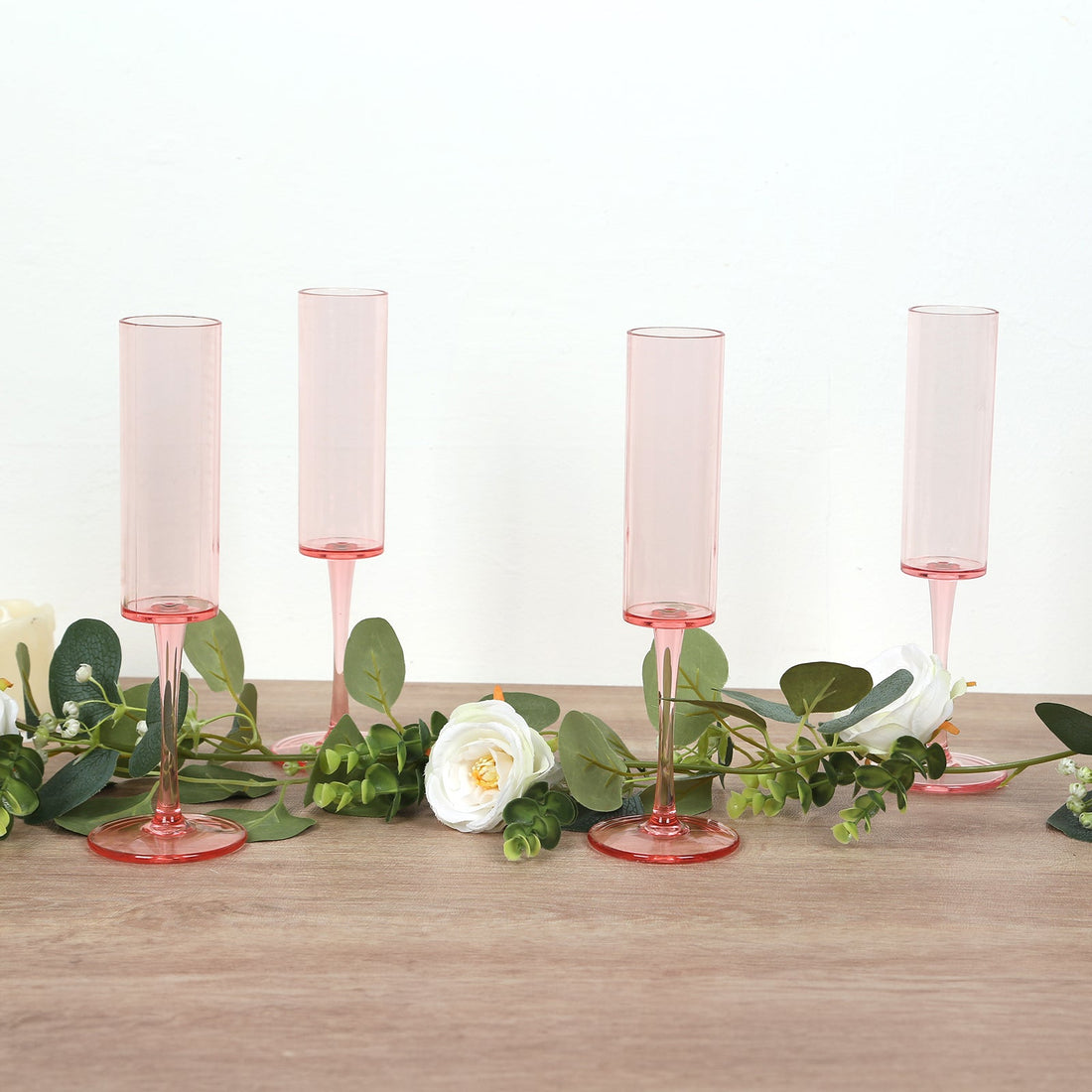 Set of four pink champagne flutes with floral decor.