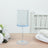 Blue stemmed glass on a wooden table with white flowers and plates.