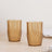 Amber patterned drinking glasses on a wooden table.