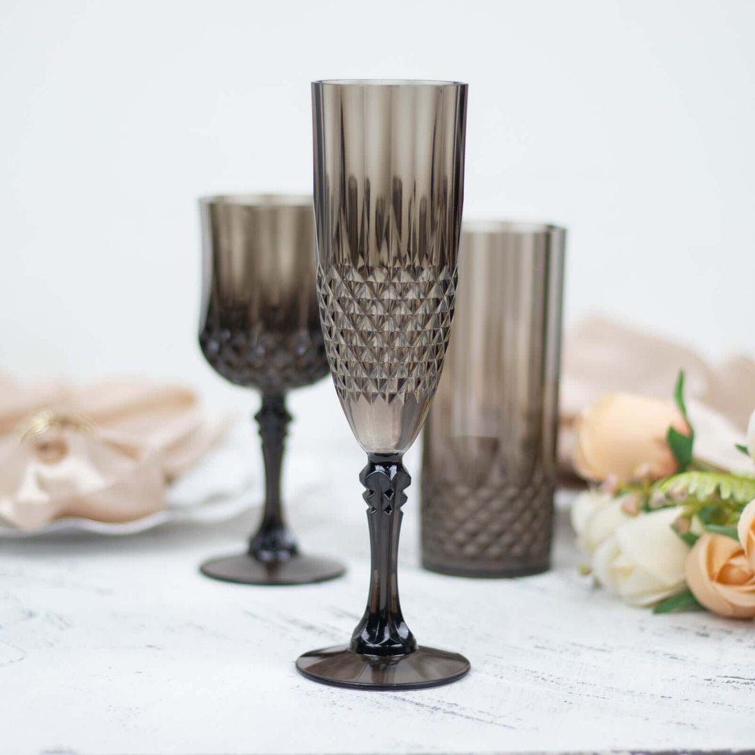 Elegant smoked glass champagne flutes with intricate patterns and black stems.