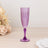Purple champagne flute on a light wooden surface with floral accents.