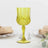 Yellow crystal goblet with intricate design on a plain background