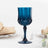 Blue crystal wine glass on a table setting with elegant napkins and plates.