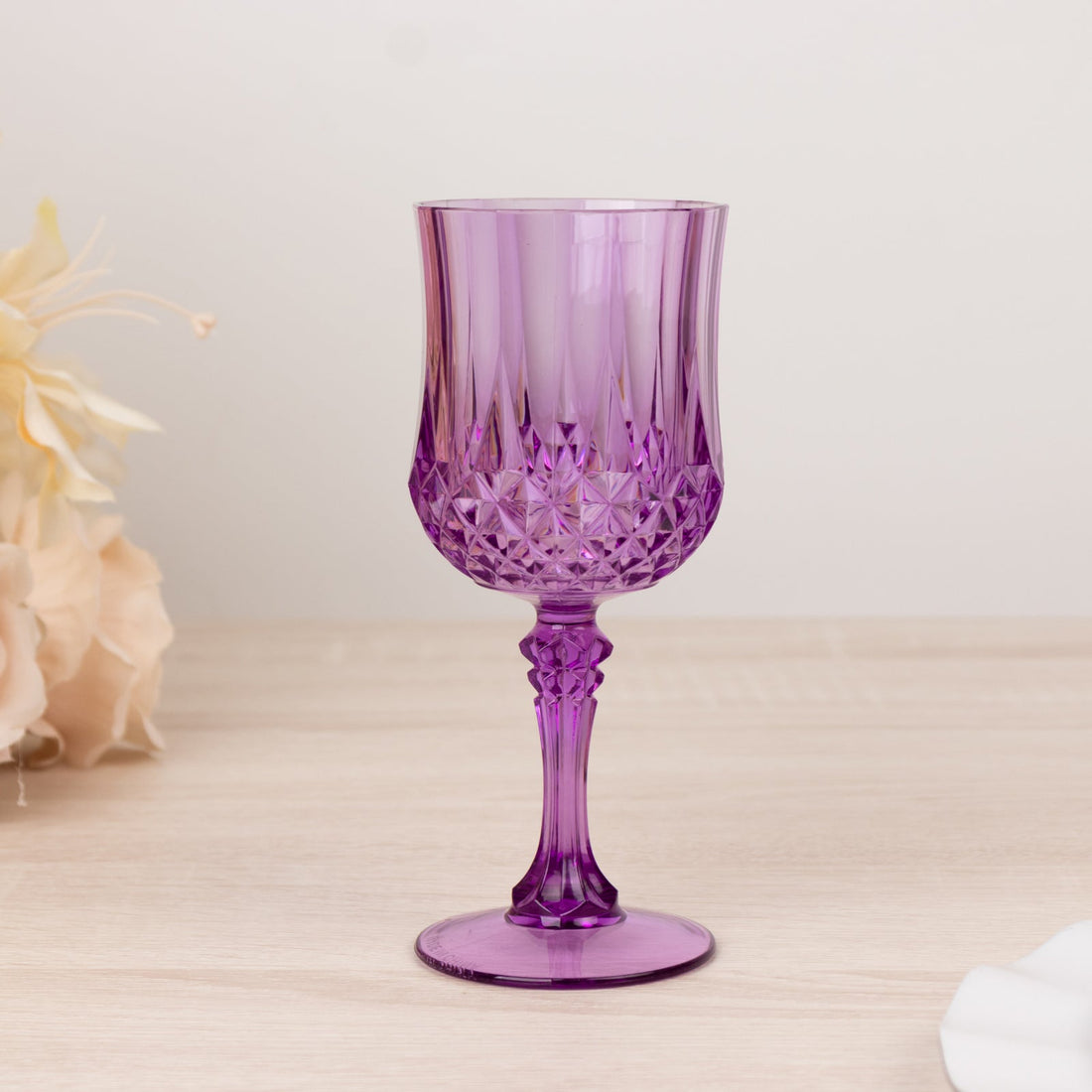 Purple crystal glass on a wooden surface with floral accents.