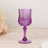 Purple crystal glass on a wooden surface with floral accents.