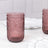 Pink embossed glass tumbler on a marble surface.