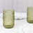 Textured green glass tumblers on a marble table with elegant white plates.