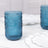 Blue vintage glass tumbler on a marble table with white plates.