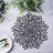 Black floral placemat on a textured surface with greenery