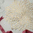 Gold floral table mat with ribbon on a plain surface.