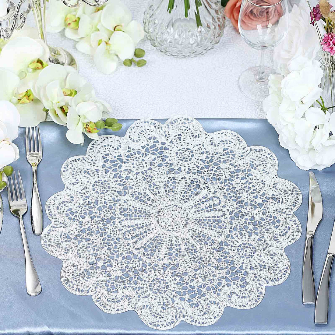 Lace table doily on a blue tablecloth with floral decorations