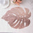 Rose gold monstera leaf placemat on a textured tablecloth.