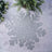 Gray snowflake placemat on a textured surface with greenery