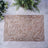 Decorative lace placemat with intricate leaf patterns on a textured surface.