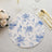 Floral blue and white round placemat on a textured table setting.