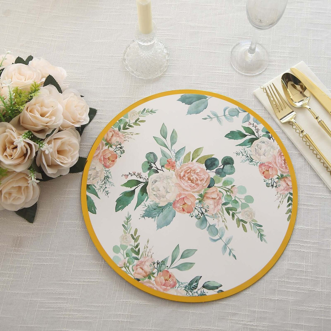 Floral decorative plate with a gold rim on a textured tablecloth.