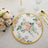 Floral decorative plate with a gold rim on a textured tablecloth.