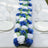 Blue and white floral table centerpiece with greenery on a dining table setting.