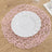 Pink woven placemat with a white plate on a wooden table.