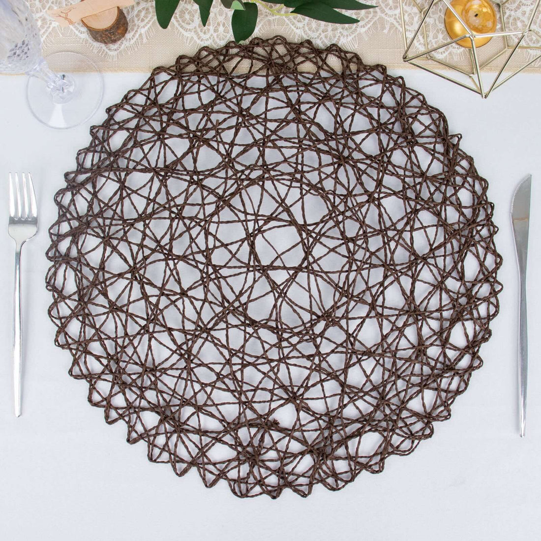 Brown woven placemat with intricate pattern on a dining table setting.