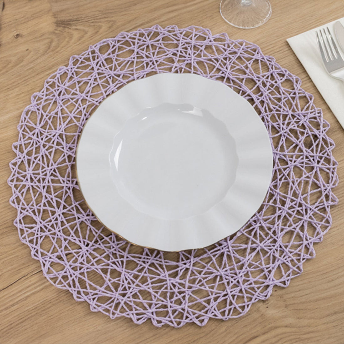 Purple woven placemat with a white plate on a wooden table.