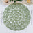 Green woven placemat in a circular design on a dining table.