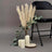 Pampas grass arrangement with candles and greenery beside a black chair.