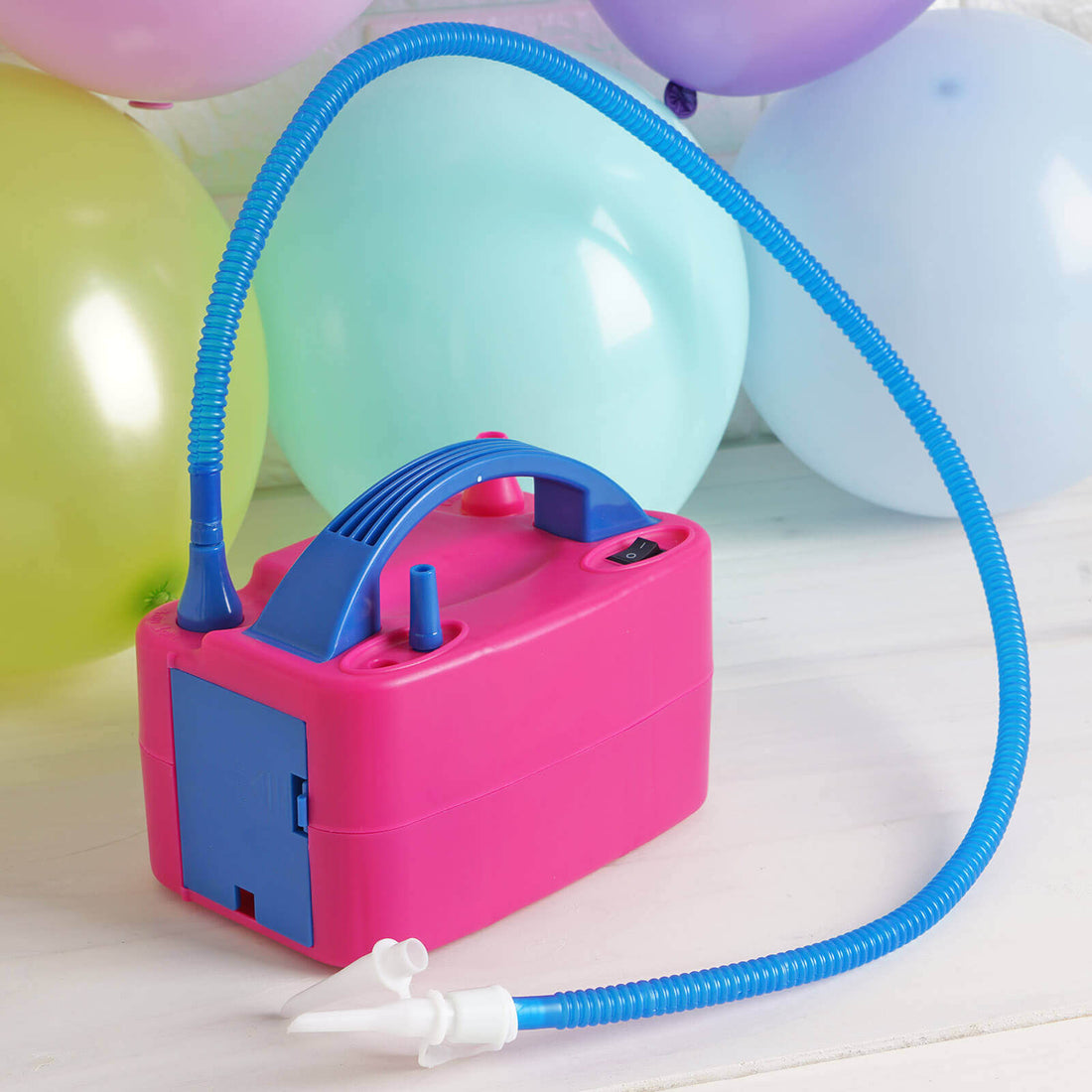 Pink balloon pump with blue hose, ideal for party decorations.