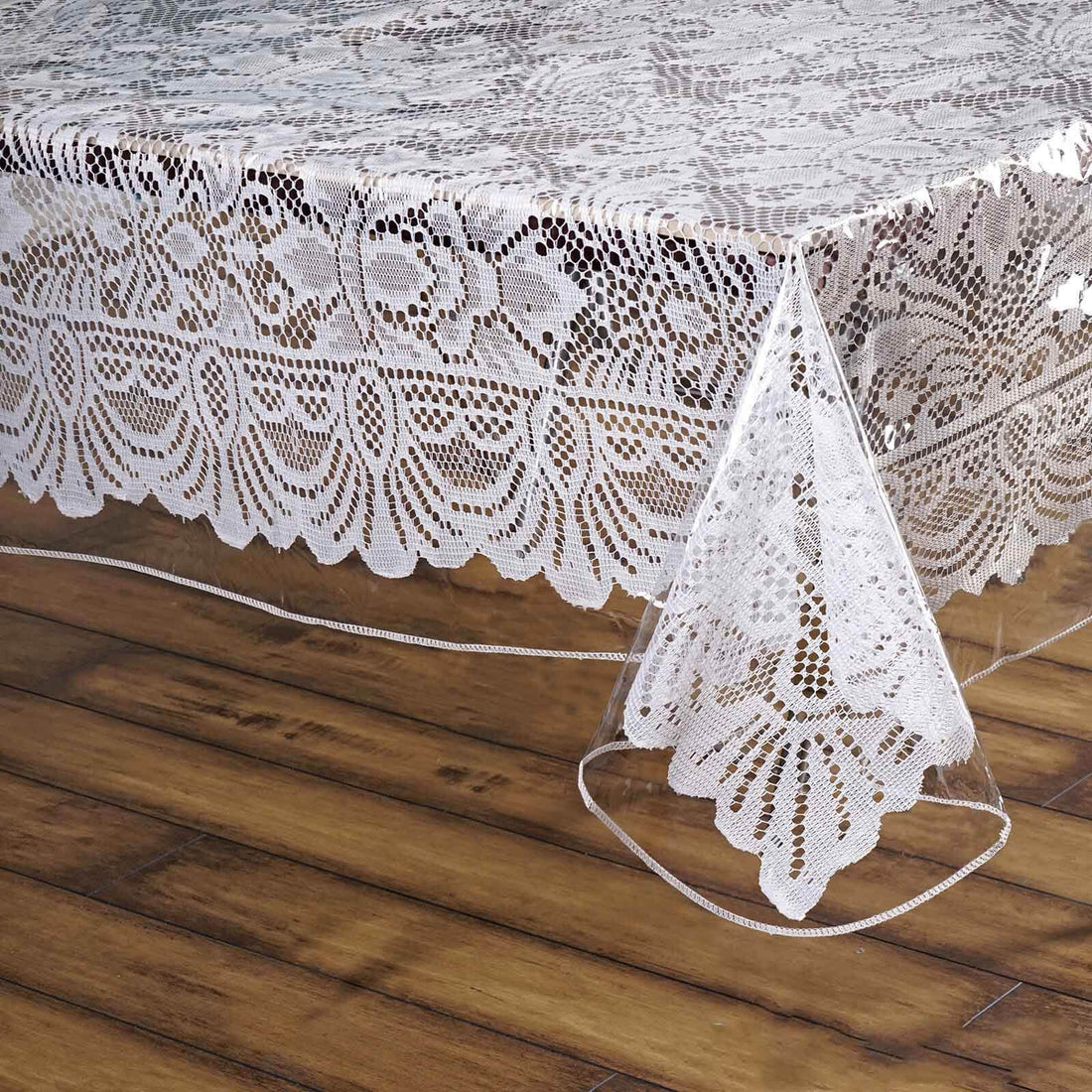 Clear lace table cover with elegant floral pattern draping over a wooden surface. #whtbkgd