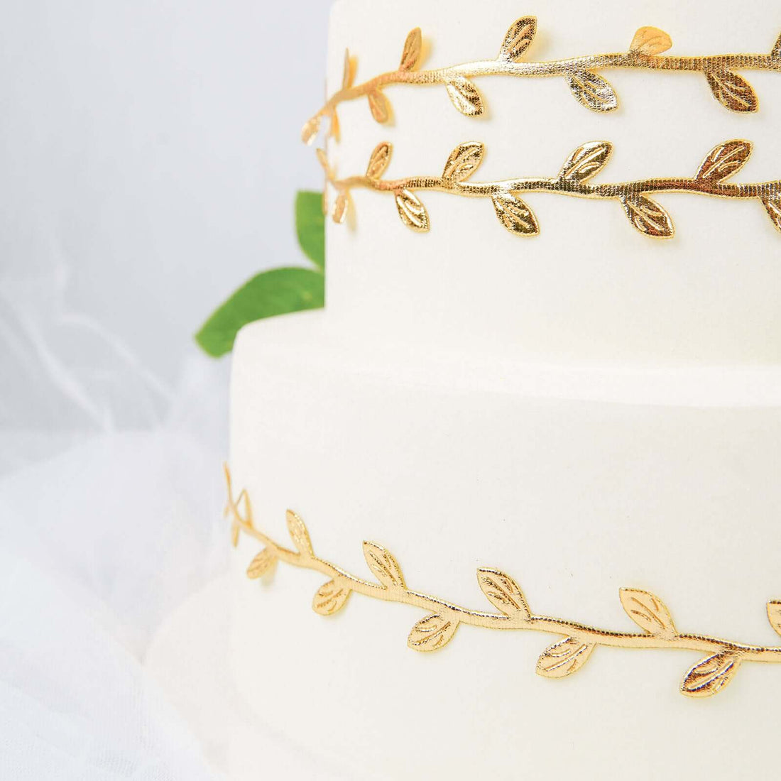 Elegant two-tiered wedding cake adorned with golden leaf details.