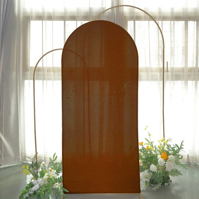 Brown fabric arch backdrop with floral arrangements, soft natural lighting.