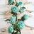 Table setting with aqua roses, plates, glasses, and silver cutlery.
