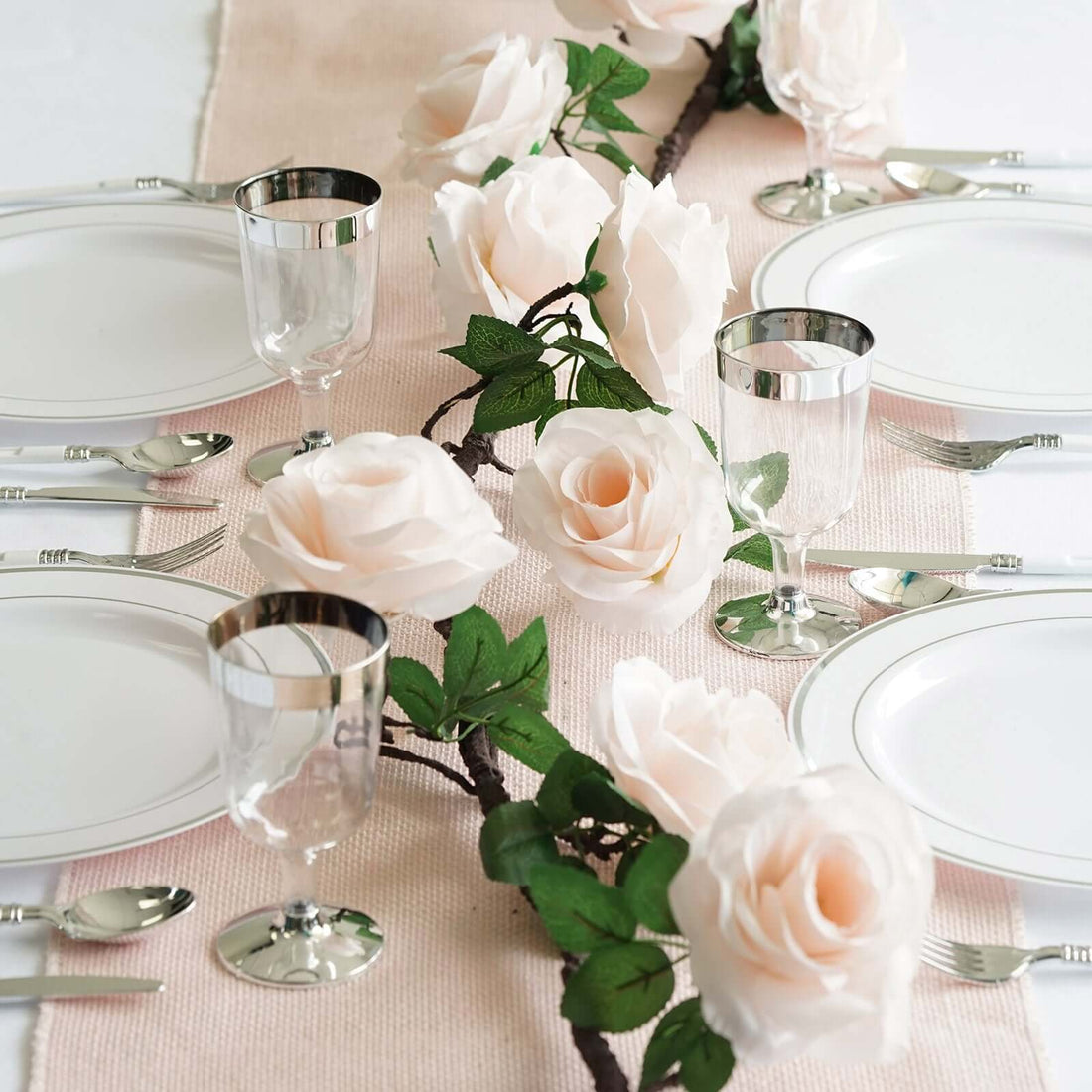 Elegant table setting with white plates, glassware, and pink roses.