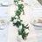 Elegant table setting with white roses and greenery centerpiece.